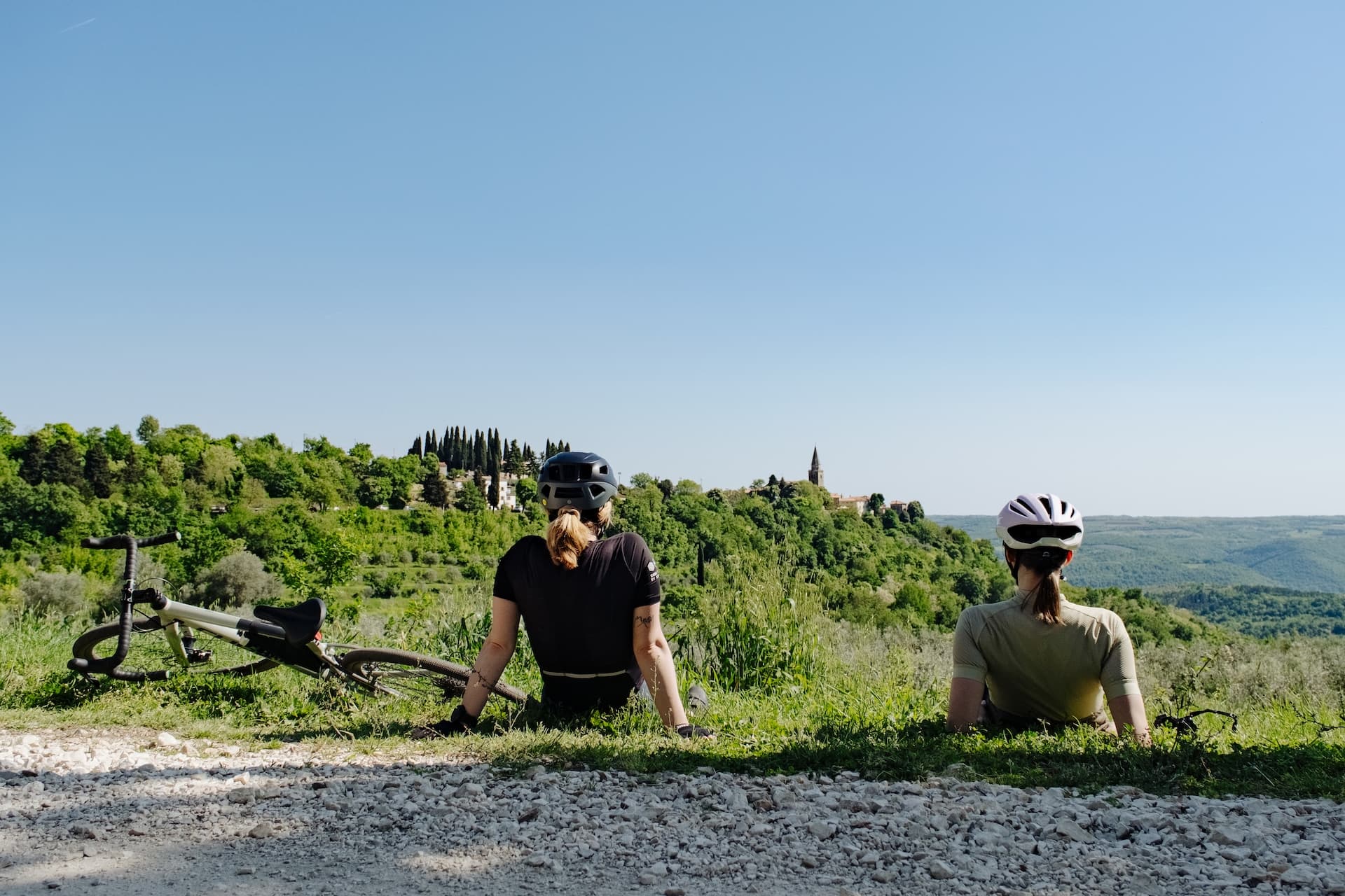 Cyclists taking a break overlooking Grožnjan viewpoint and rolling green hills.