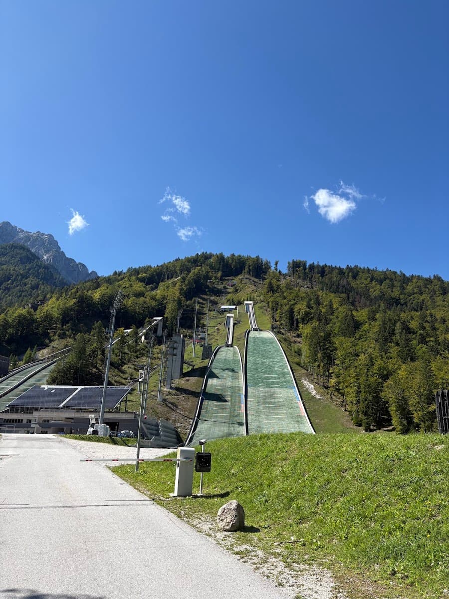 Ski jump ramps on a lush green mountain slope under a blue sky