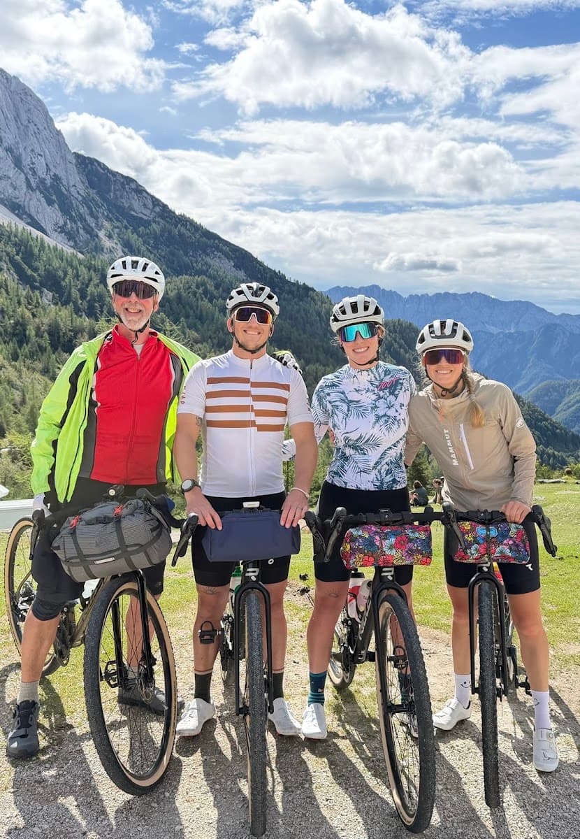 Cyclists with gravel bikes posing on mountain trail with alpine peaks