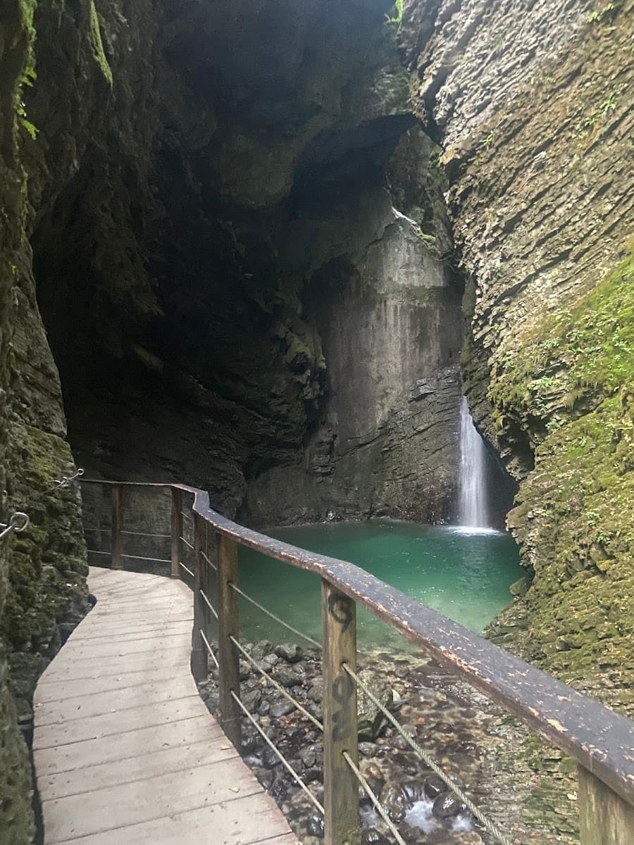 Wooden boardwalk along rocky gorge with waterfall flowing into pool