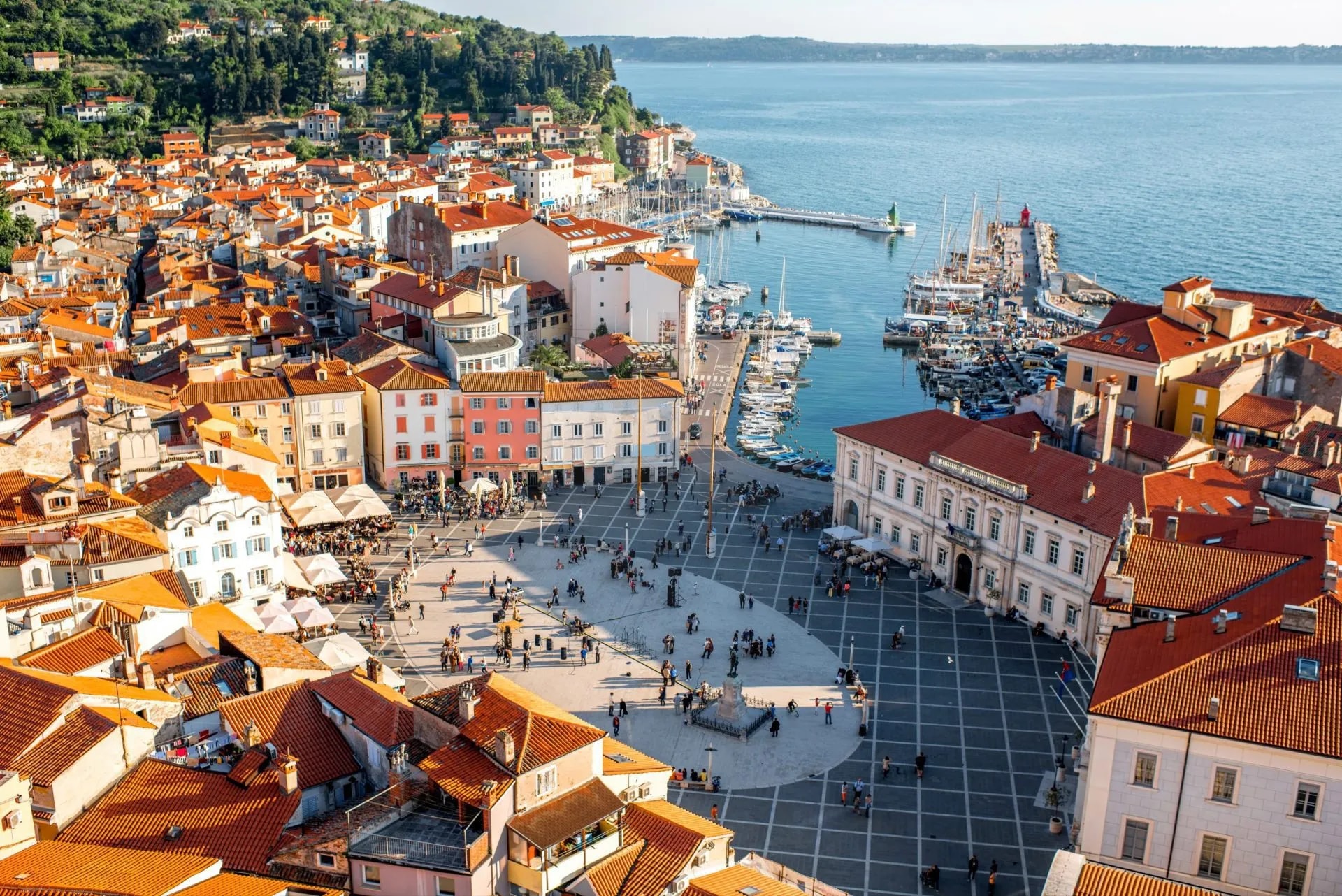 Aerial view of Piran town square, red roofs, and Adriatic Sea with boats in southwestern Slovenia.