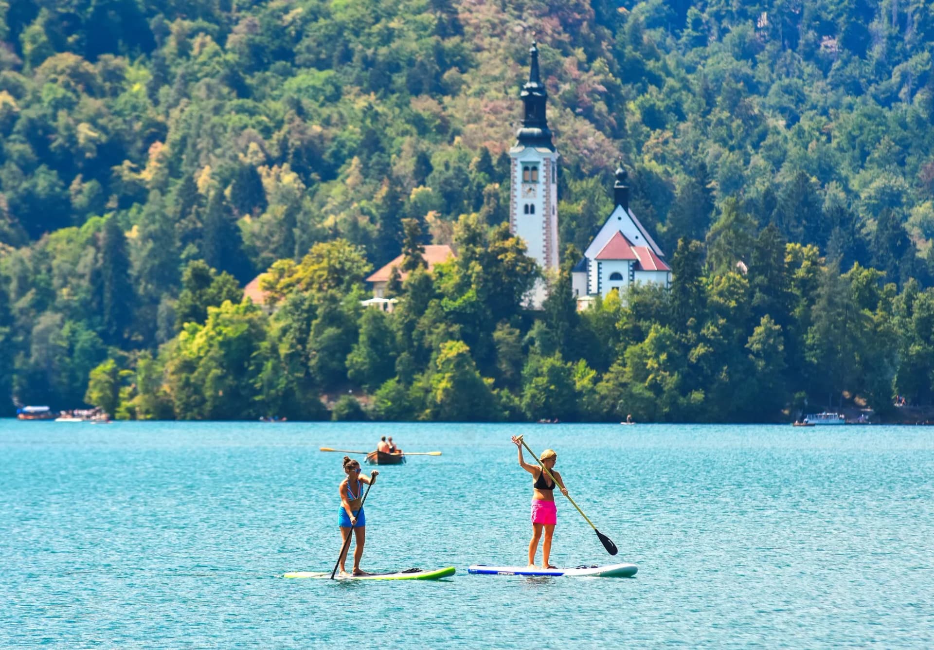 Paddleboarding on Lake Bled with the island church visible among the dense green forest.