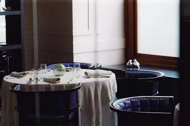 Set dining table with white linen and blue chairs inside a restaurant in Ljubljana.