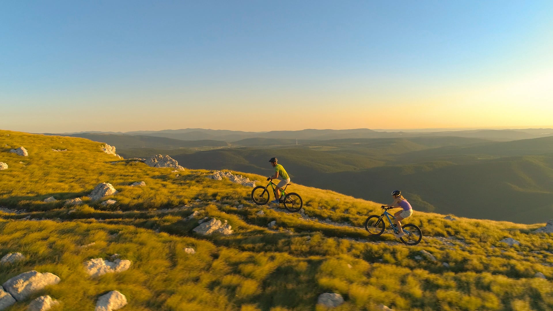 DRONE: Sporty young couple mountain biking along a scenic path in Slovenia.