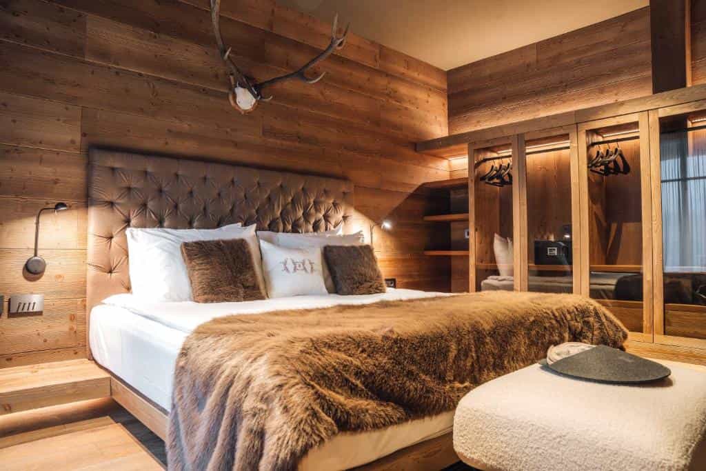 Bedroom with wooden walls, tufted headboard, and faux fur throw in an alpine-style room.