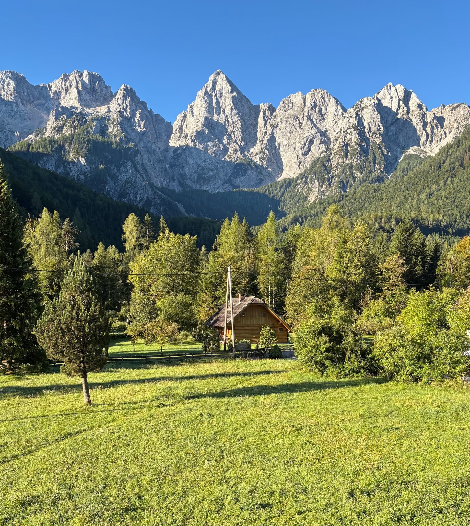 Julian Alps rocky mountain peaks rising above a green meadow and cabin