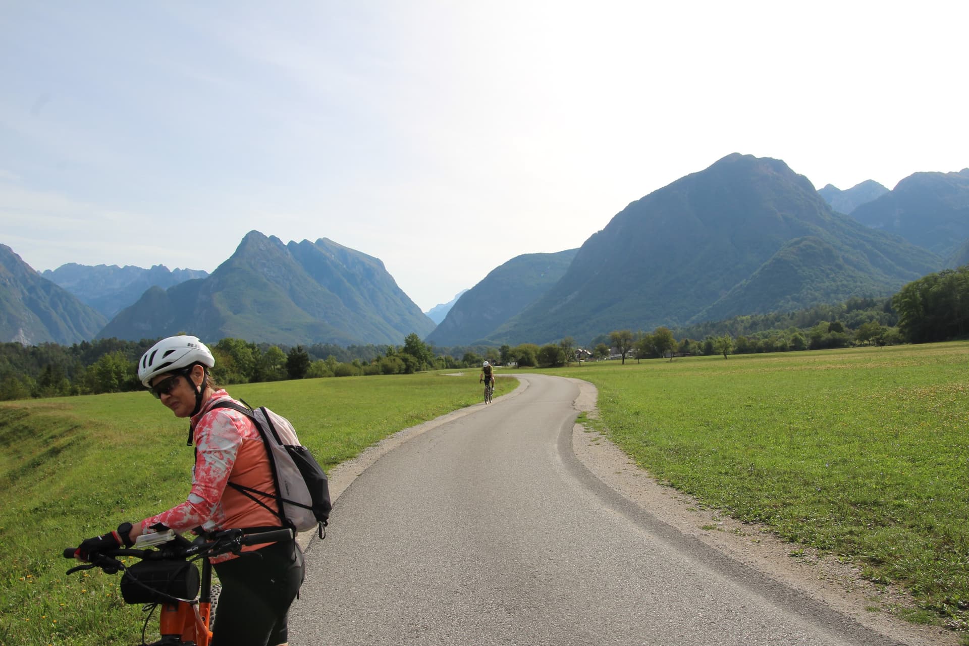 Cyclist on meadow road with mountain peaks in the background