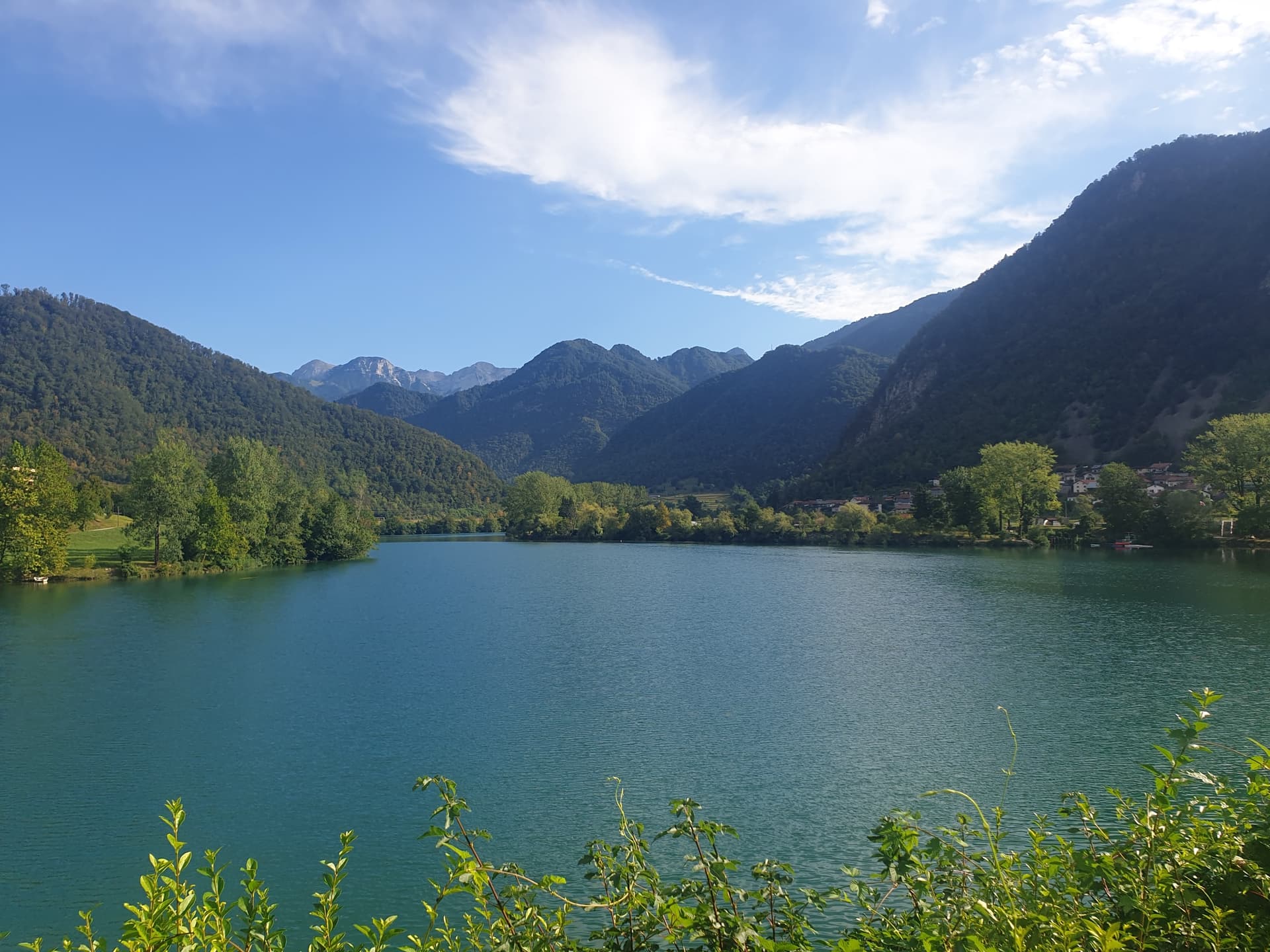 Soča Valley green lake with forested mountains and blue sky