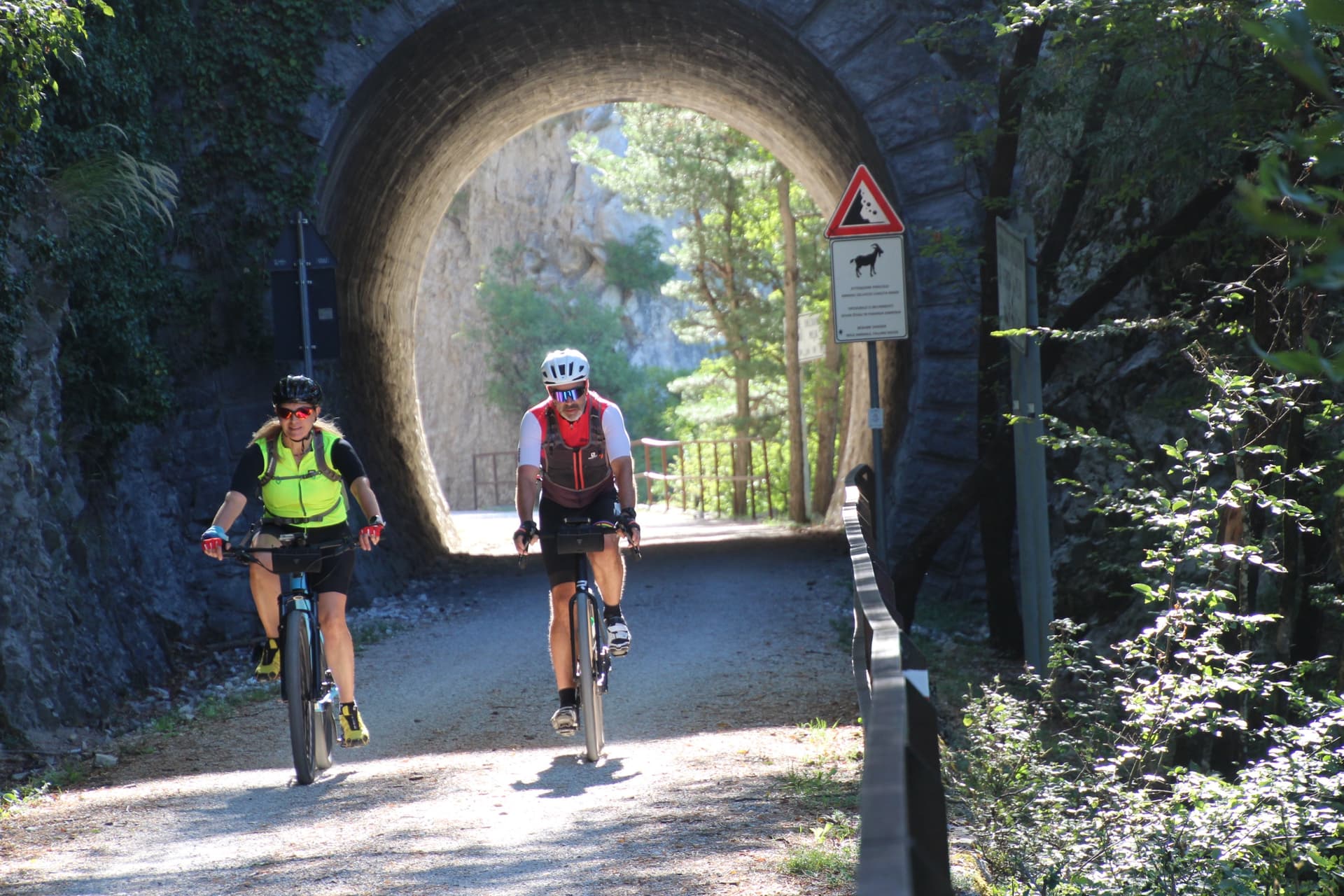 Cyclists riding through an old railway tunnel on a paved path