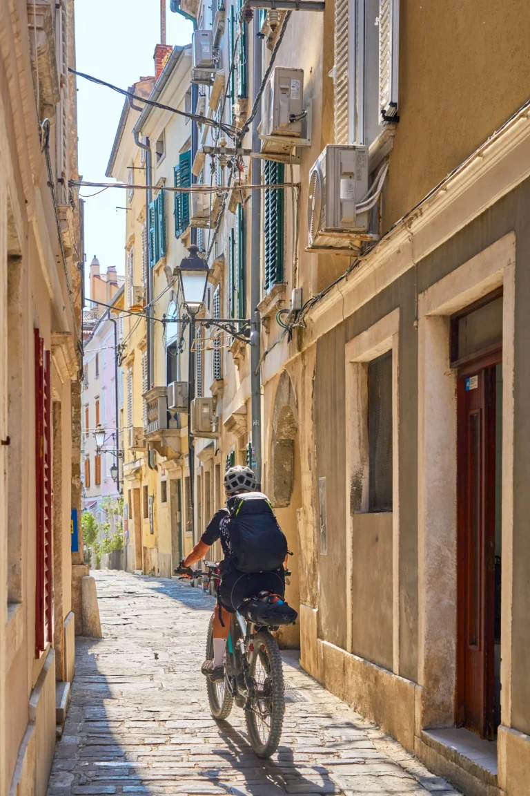 mooie senior vrouw fietsen in het centrum van Piran aan de Adriatische zee in Slovenië, Europa