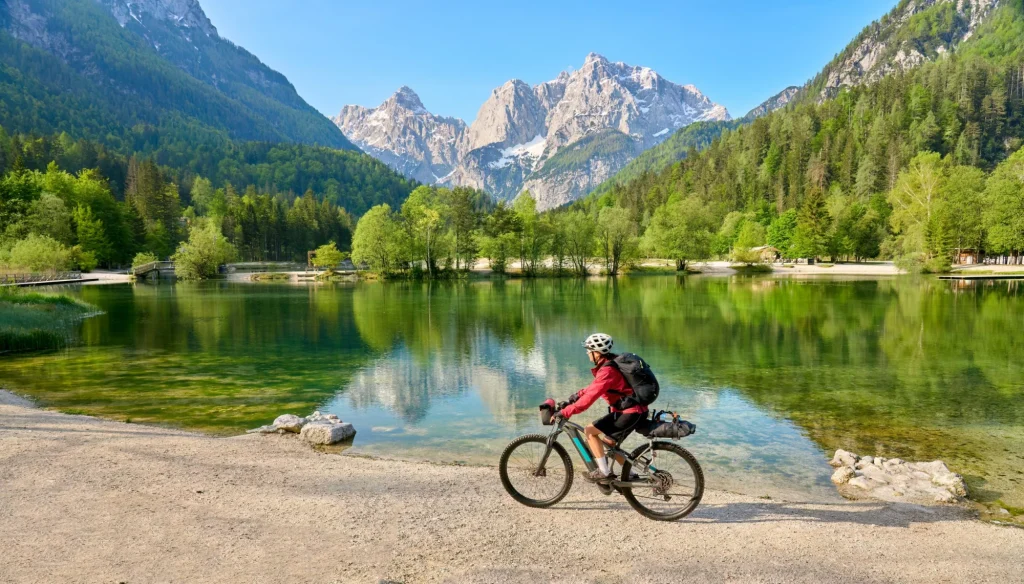 Mujer mayor activa en una excursión en bicicleta de montaña en el lago Jezero Jasna, en el Parque Nacional de Triglav, cerca de Kranska Gora, Alpes Julianos, Eslovenia.