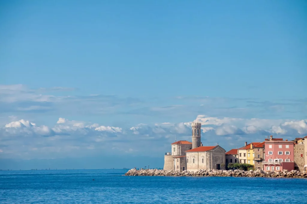 Panorama de Piran, Eslovenia, con el mar Adriático al frente, con el agua y el cielo azules, en un muelle embarcadero, durante una soleada tarde de verano. Piran, o Pirano, es una ciudad eslovena a orillas del mar Adriático, en Istria.